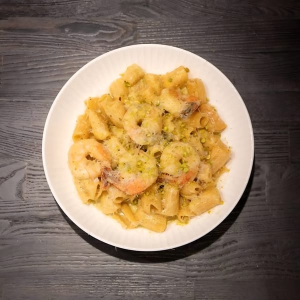 BASTA Pasteria's rigatoni pasta with shrimp, parmesan, and pistachio, served in a white bowl.